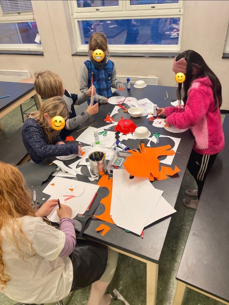 En gruppe barn som sitter rundt et bord og lager snømenn.