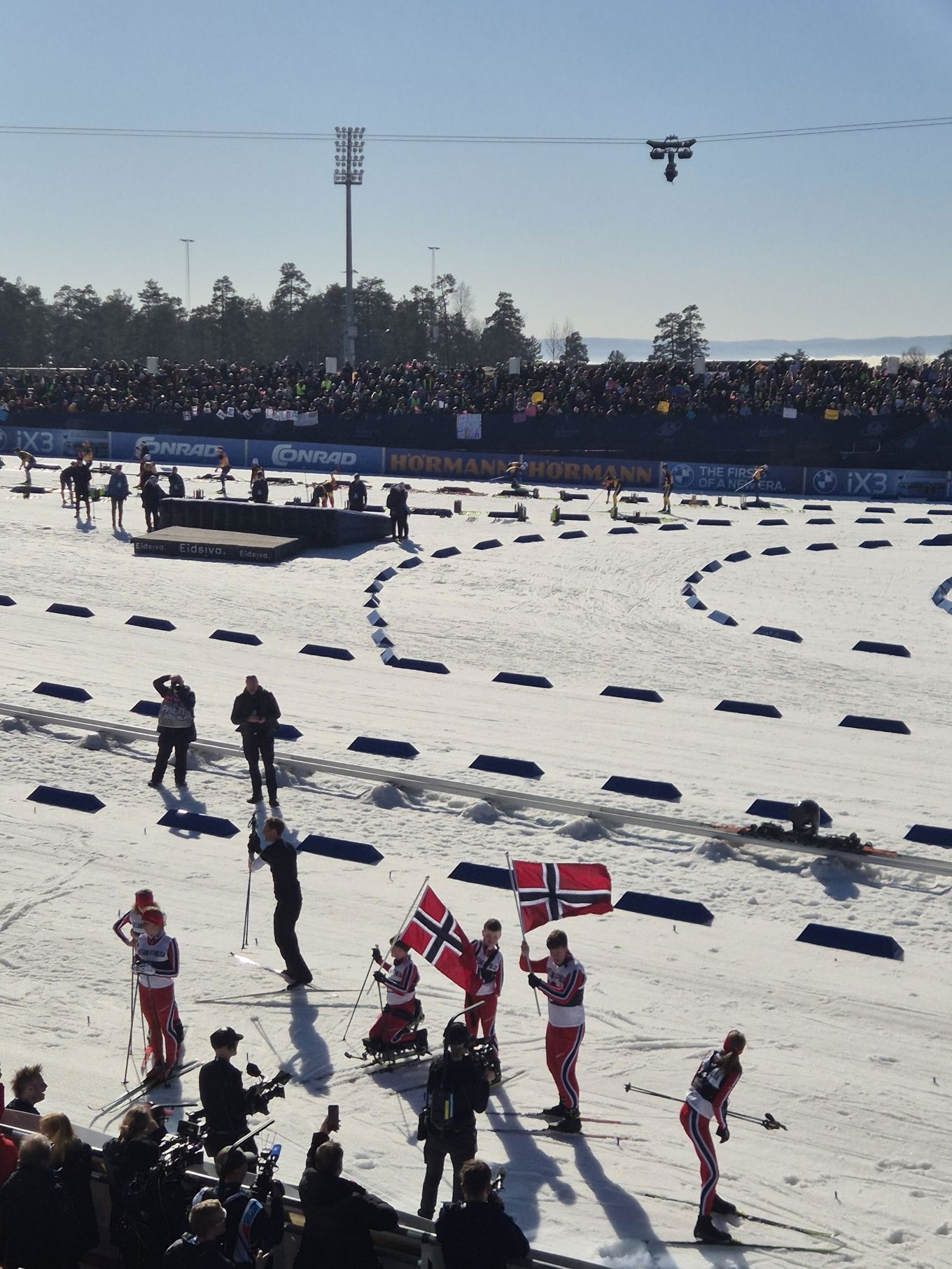 En gruppe mennesker som står på ski på snøen og har flagg